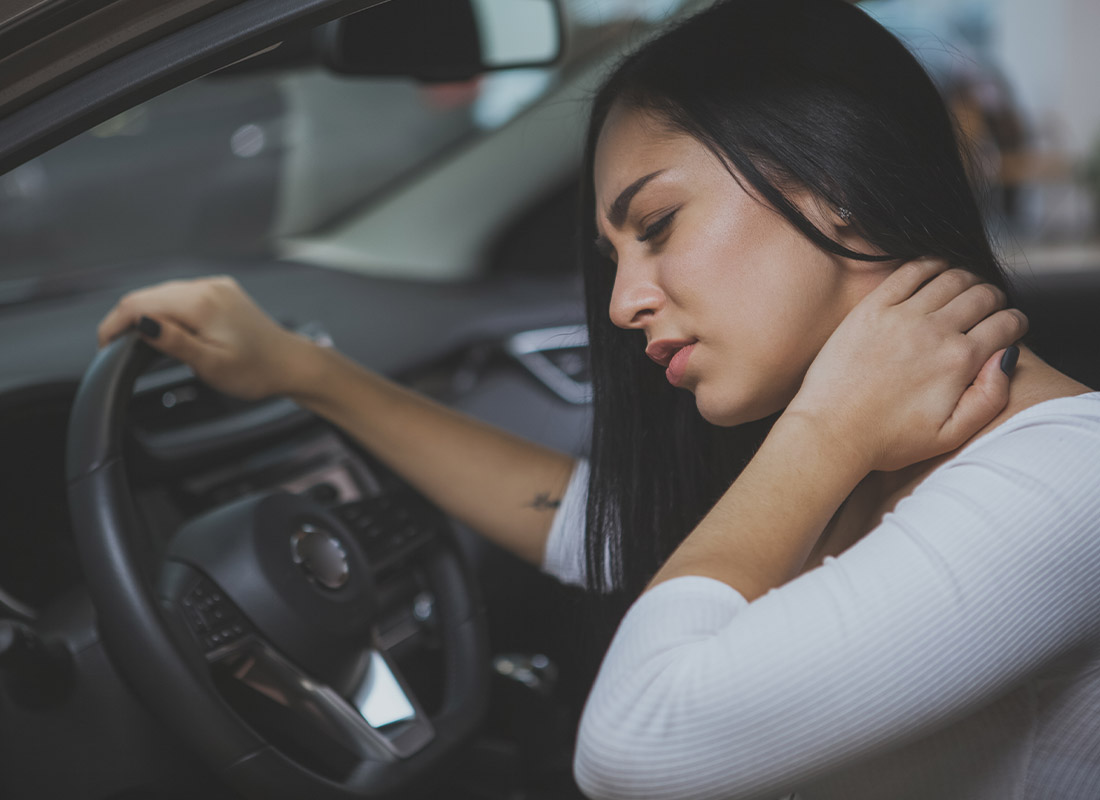 Personal Injury Protection (PIP) Insurance - Young Woman Rubbing Her Neck and Feeling Sore After Whiplash in a Car Crash